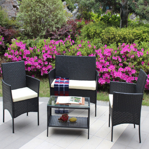 Four-piece rattan patio sofa set with beige cushions and coffee table